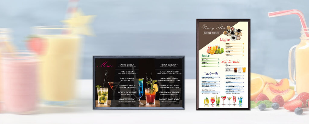 Two digital menu boards against a background of colorful smoothies and fruits. The left board shows a dark-themed cocktail menu, while the right displays a light-themed drink menu with coffee, juice, and soft drinks. These demonstrate wireless and WiFi digital signage in hospitality for energy-efficient and sustainable solutions.